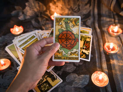 Hand holding tarot card with candlelight on the darkness background