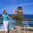 A couple taking picture on the deck of cruise ship at sea.