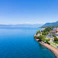 a beautiful town on a lake, with mountains in the background 