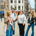 A group of young people standing around a tour guide in a European city. 