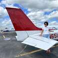 a woman standing in front of a small red and white Cessna plane 