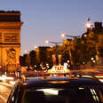 Paris taxi driving past Arc de Triomphe at dusk